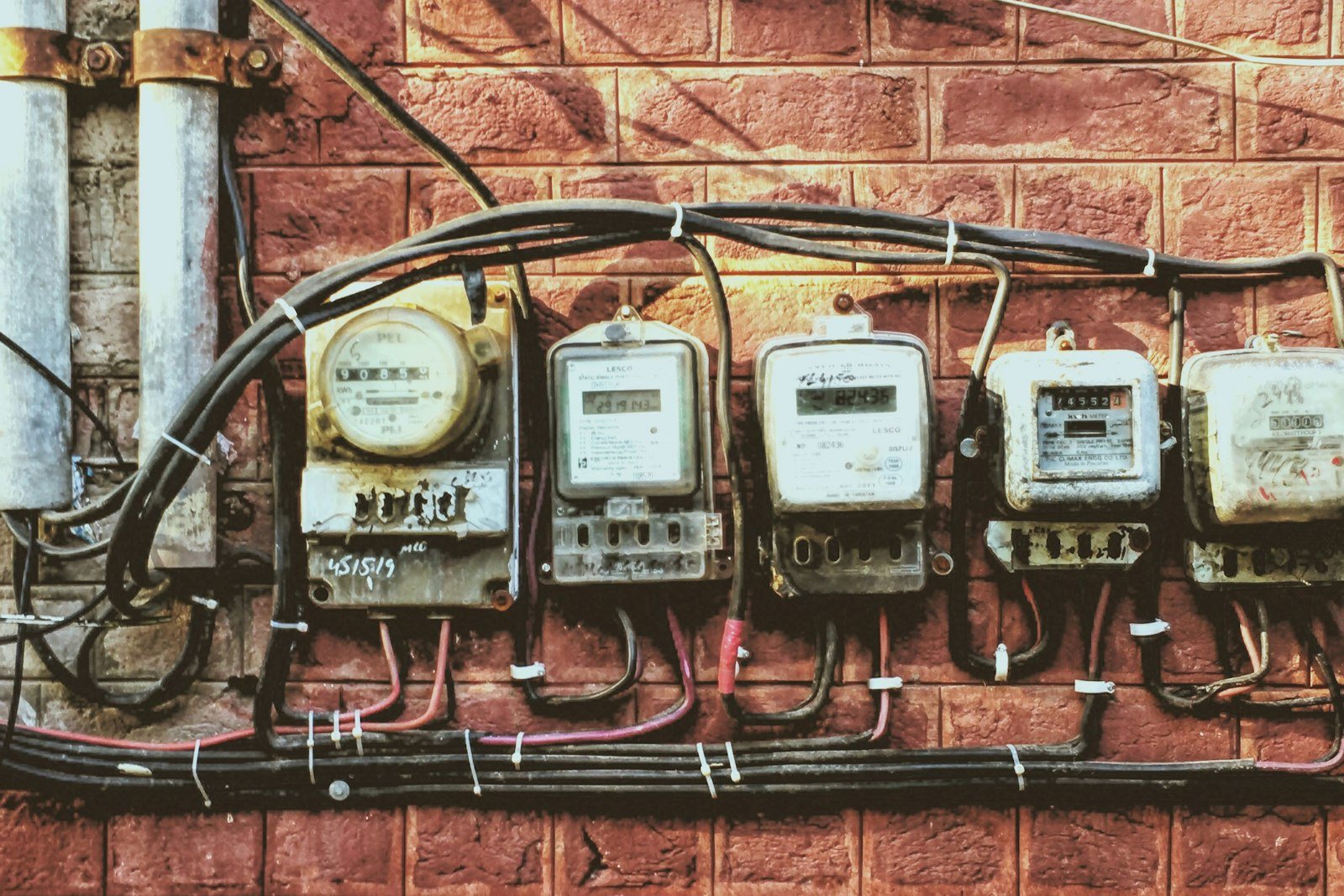 A row of electric meters on a brick wall